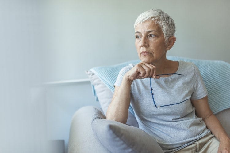 ältere Frau, die aus dem Fenster schaut, in Gedanken versunken, weil sie nach einem Schlaganfall Angst hat