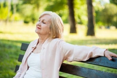 femme assise sur un banc avec les yeux fermés méditant
