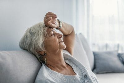 Frau sieht erschöpft auf der Couch aus
