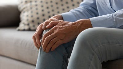  ältere Frau mit Knieschmerzen aufgrund steifer Muskeln
