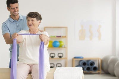 Un physiothérapeute aide une patiente à effectuer des exercices de rééducation pour se guérir après son AVC.