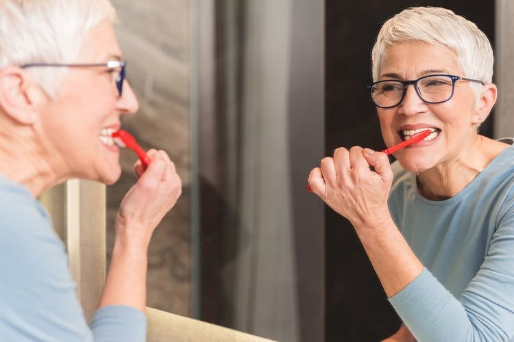 Une patiente qui brosse les dents symbolise le sujet de cet article : comment faciliter les tâches journalières après un AVC.